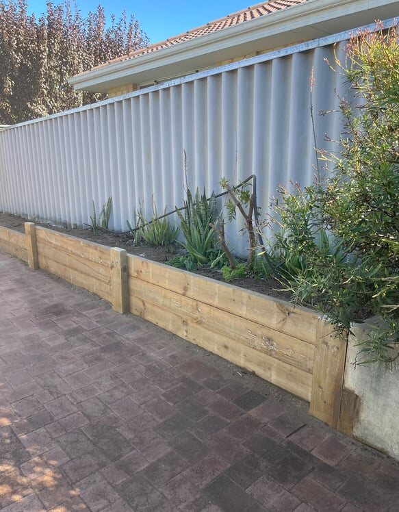 Completed timber garden retaining bed beside a strata boundary fence